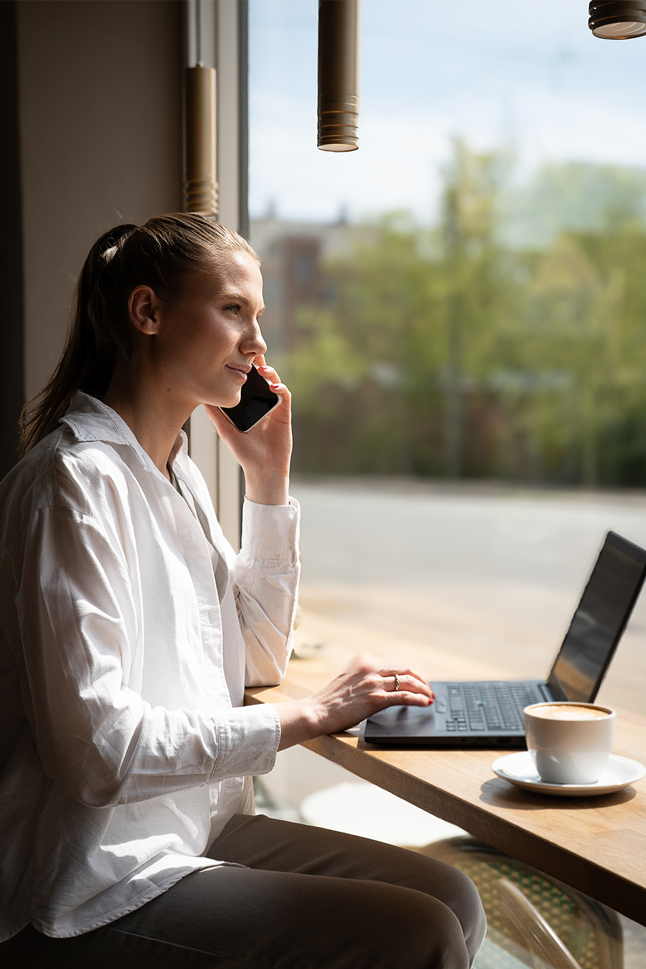 Medarbejder sidder på café med sin pc og taler i telefon